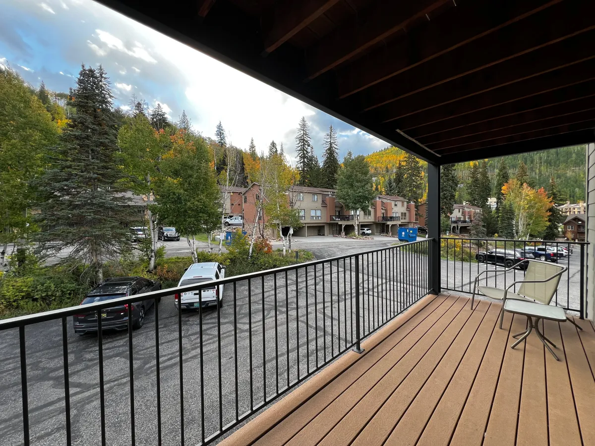 A relaxed exterior view from a balcony overlooking lush foliage, with the inviting prospect of enjoying morning coffee, reading, or simply soaking up the mountain air.