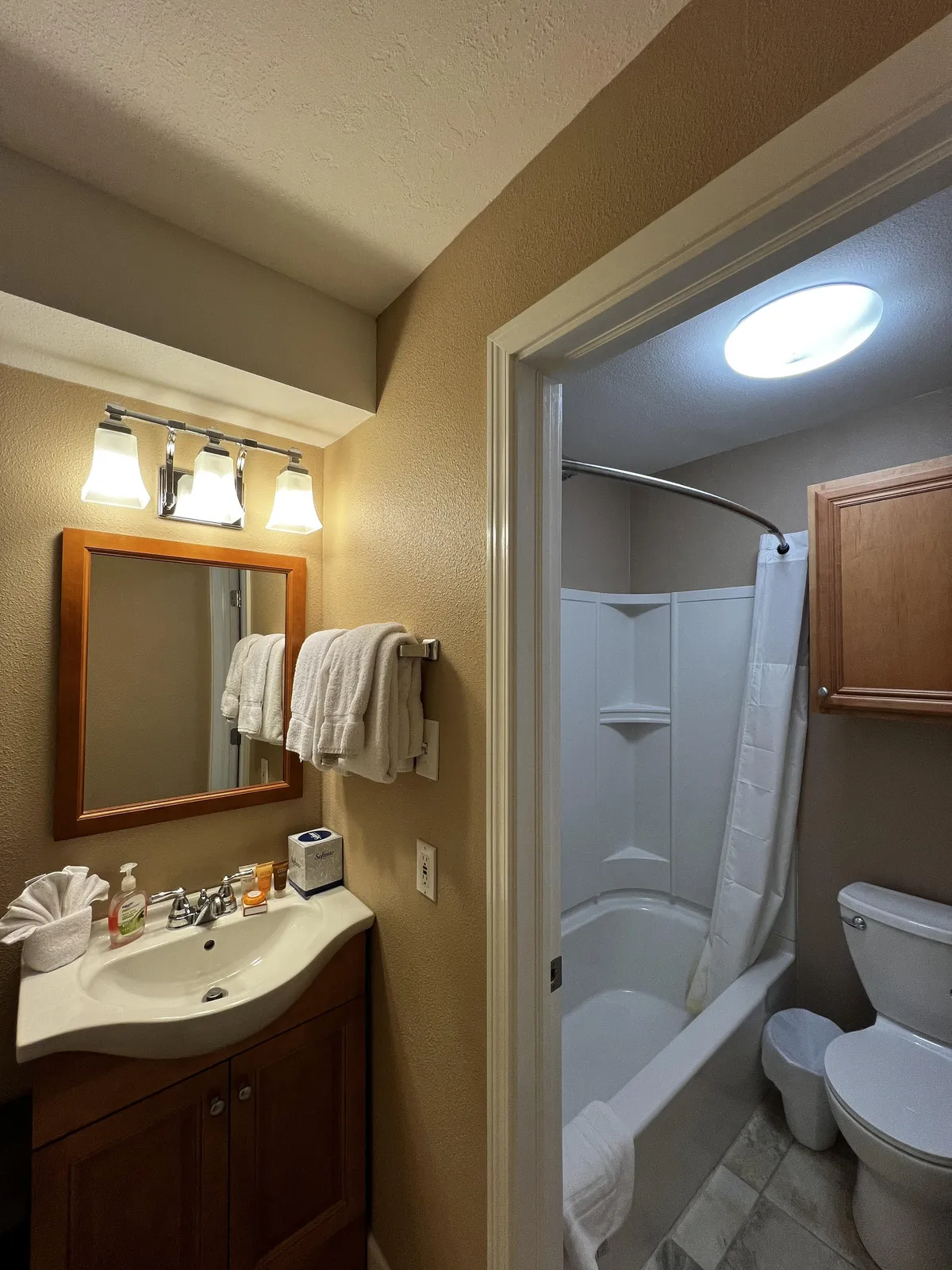 This image displays a serene bathroom scene with a sink, mirror, shower, toilet, and neatly arranged towels. The space feels calm, clean, and spa-like, emphasizing both functionality and relaxation.