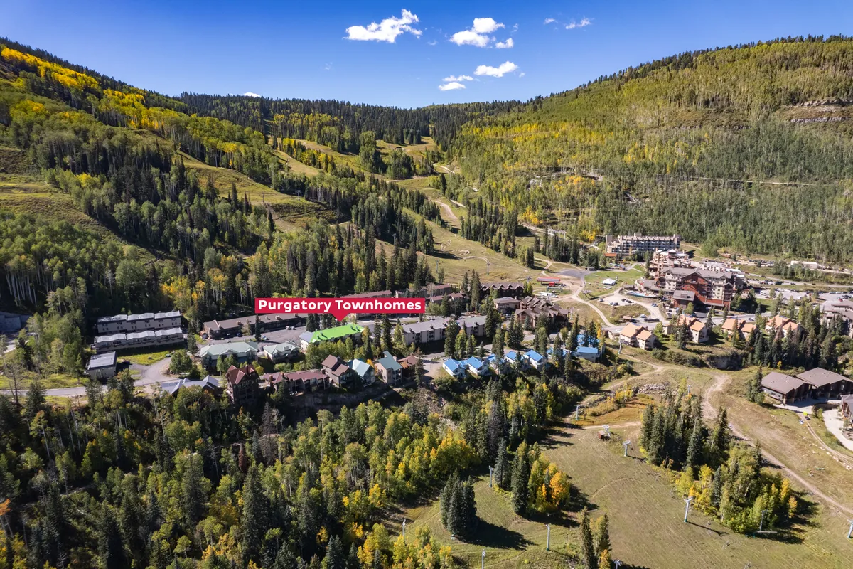 A sweeping view of Purgatory Townhomes nestled among lush forests and dramatic mountain ridges, with ski slopes visible in the distance. The image captures the expansive natural setting and accessibility to surrounding trails, perfectly encapsulating the property's proximity to outdoor adventure.